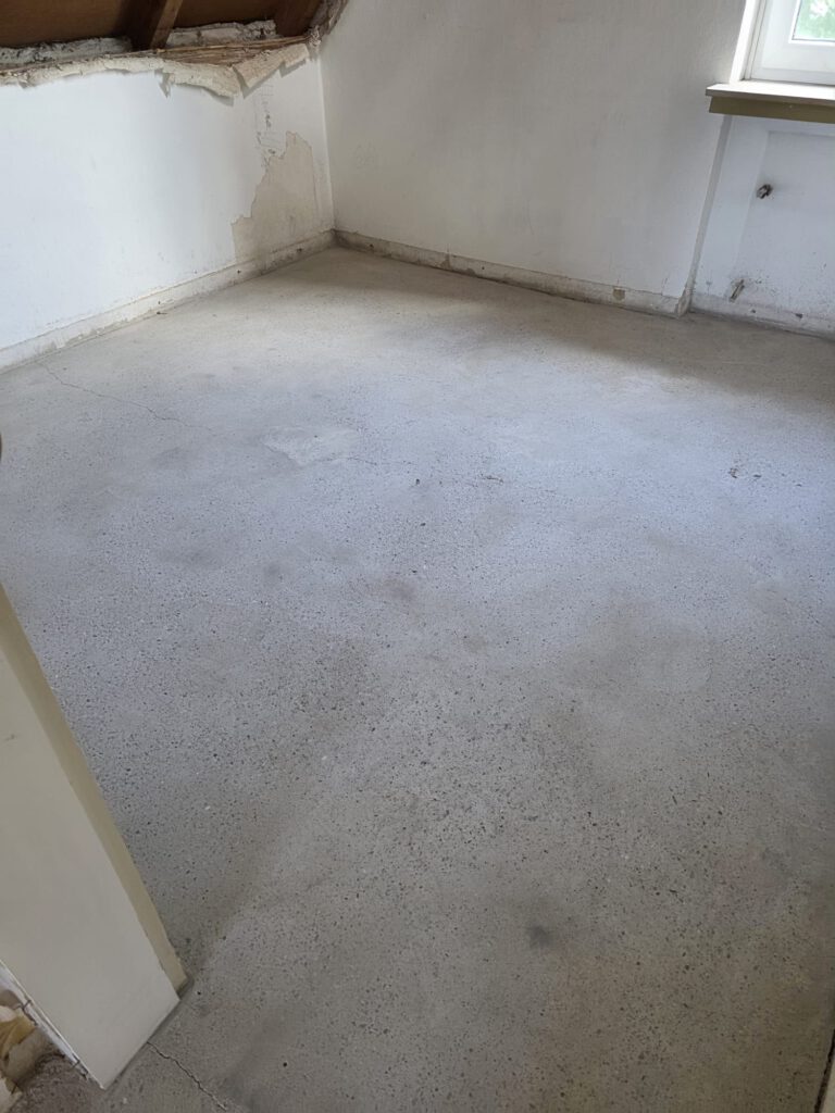 Raum mit sichtbarem Asbestboden und beschädigter Wand