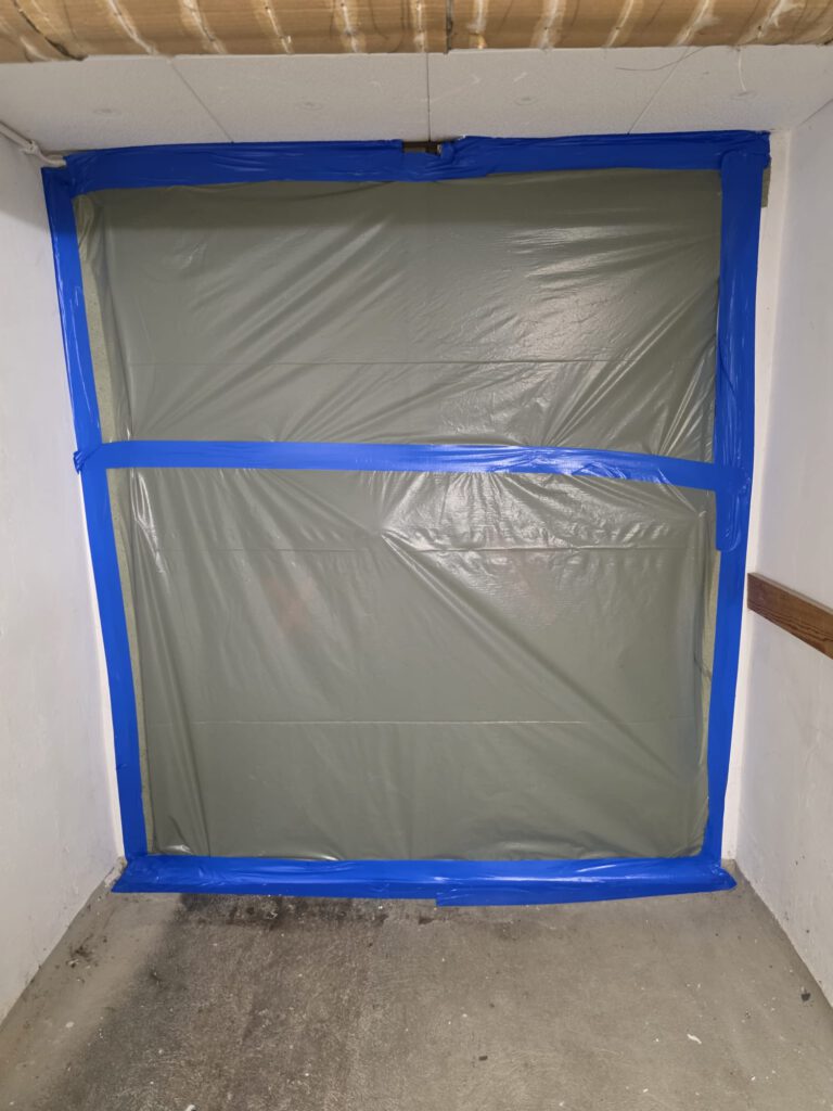 Abgeschotteter Raum mit Schutzfolie und blauen Klebebändern bei Asbestsanierung