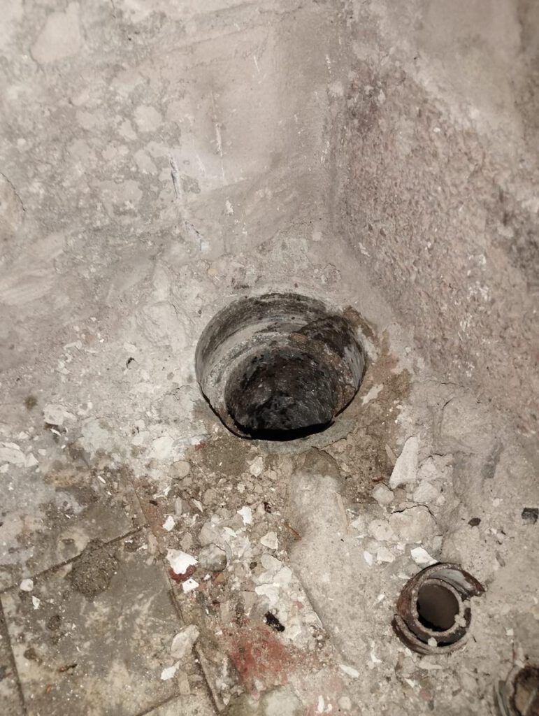 Freigelegter Asbestboden mit Rohröffnung und Bauschutt