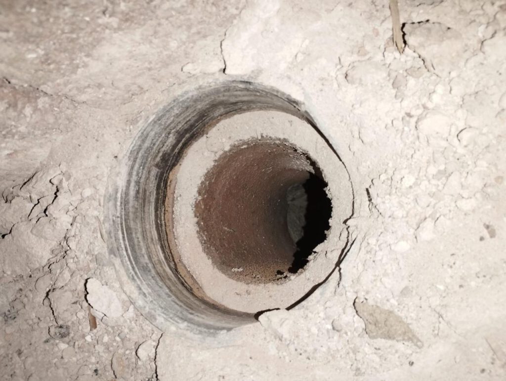 Altes Asbestrohr in einer Wandöffnung mit Staub