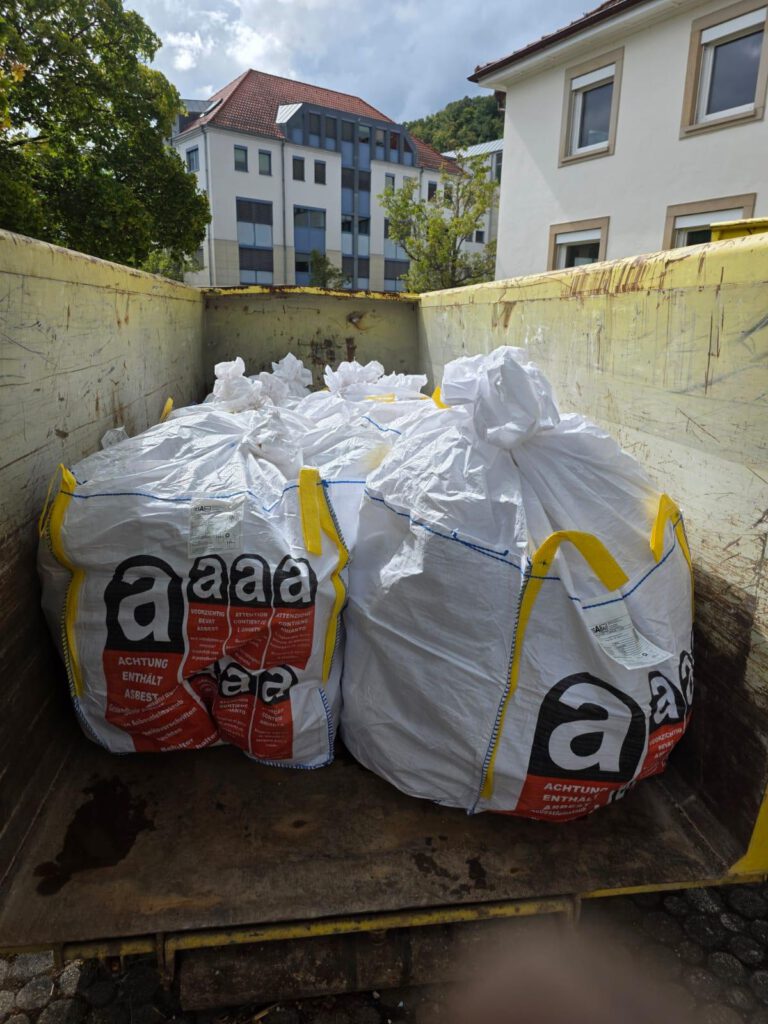 Mehrere weiße Säcke mit Warnhinweisen in einem gelben Container