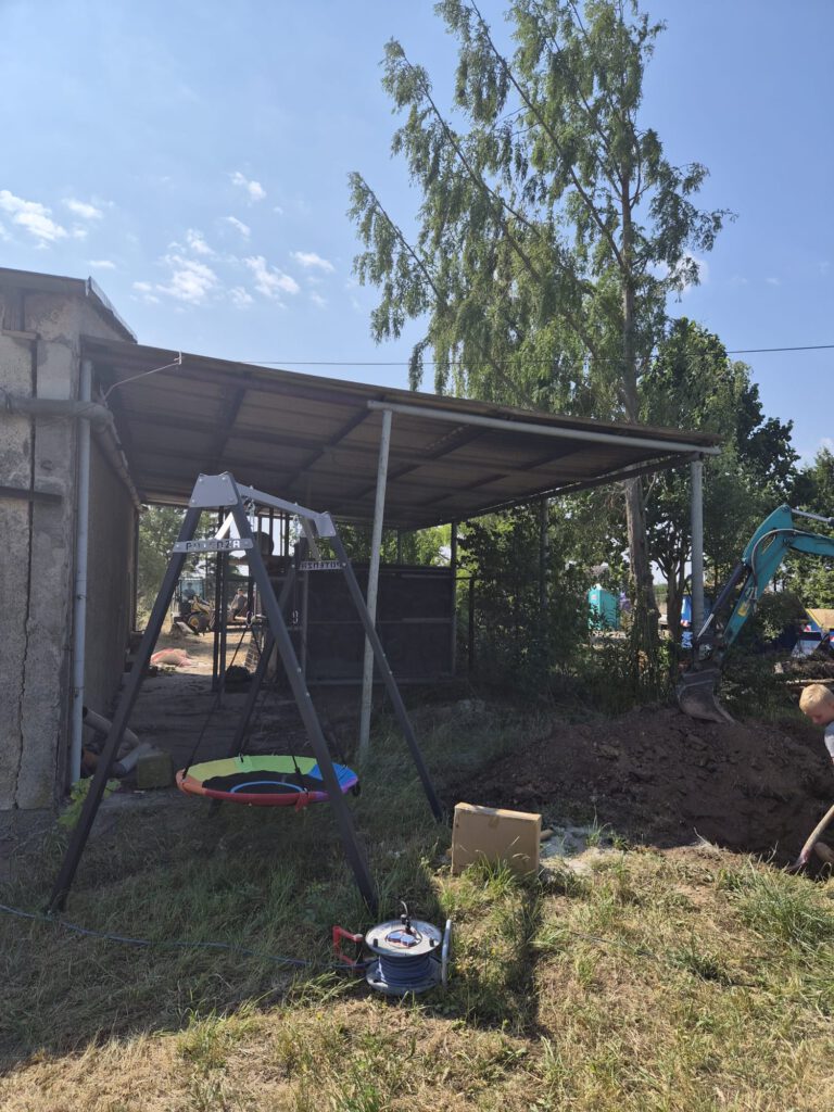 Metallgestell mit bunter Schaukel vor Dach mit Metallplatten