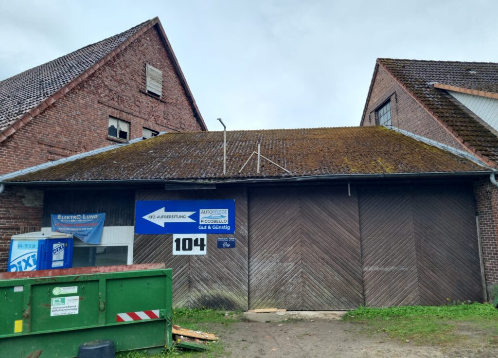 Gebäude mit vermoostem Asbestdach und Holztoren