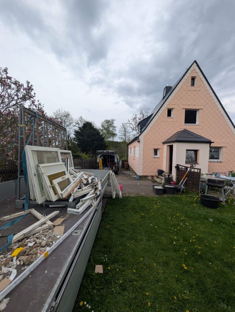 Abgebaute Fensterrahmen und Bauschutt auf einem Anhänger bei Asbestsanierung