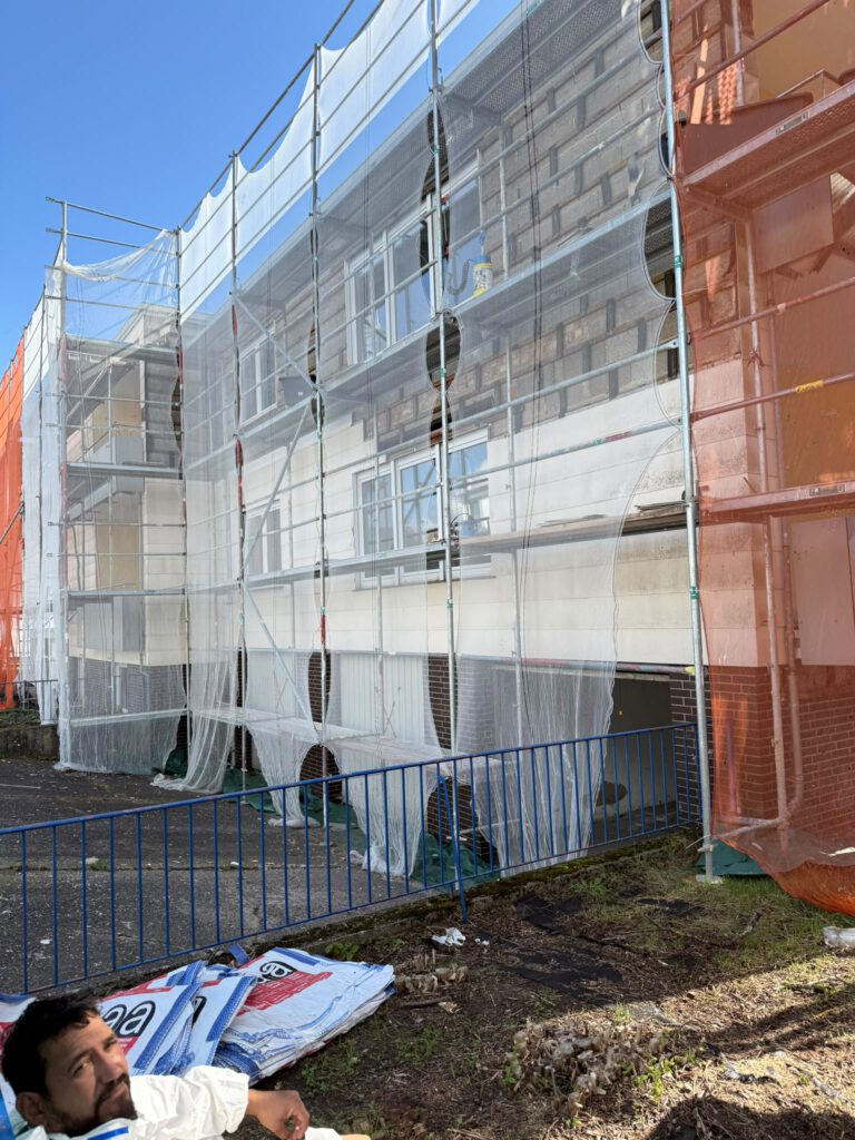 Hausfassade mit Gerüst und Schutznetz bei Asbestsanierung