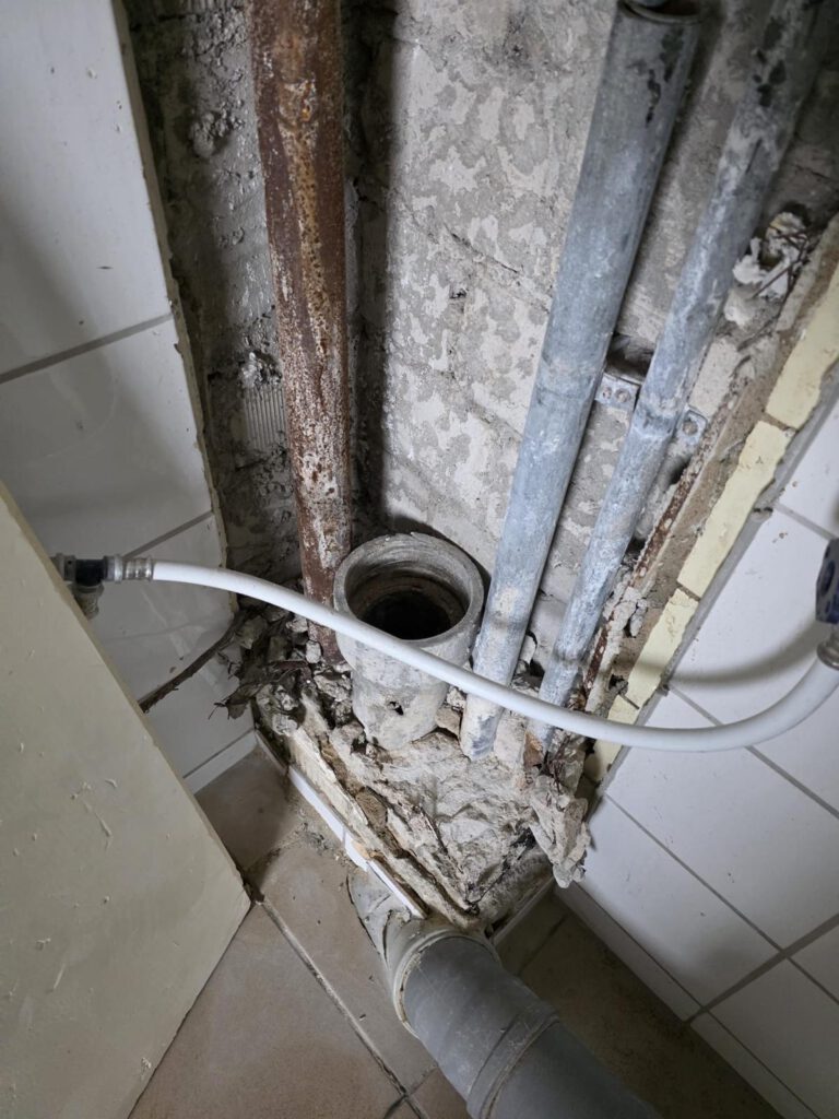Alte Rohre und Asbestrohre in Innenraum mit Abbruchspuren