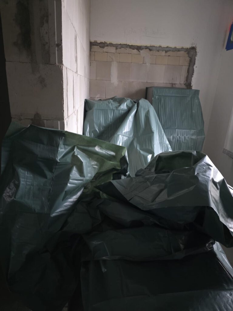 Grüne Schutzbeutel mit eingepackten Asbestplatten im Innenraum